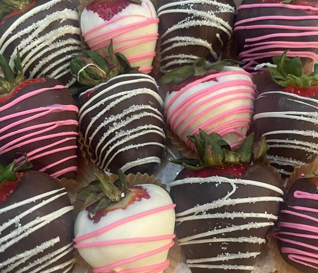 Dark, milk and white chocolate strawberries with white and pink swizzles sprinkled with sugar.