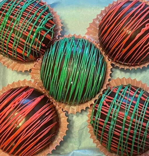 Milk chocolate cocoa bombs covered with green and red swizzles.