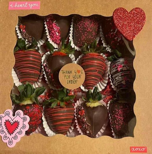A Valentines day assortment in a gift box. The strawberries are milk chocolate decorated with various red, white and pink designs.