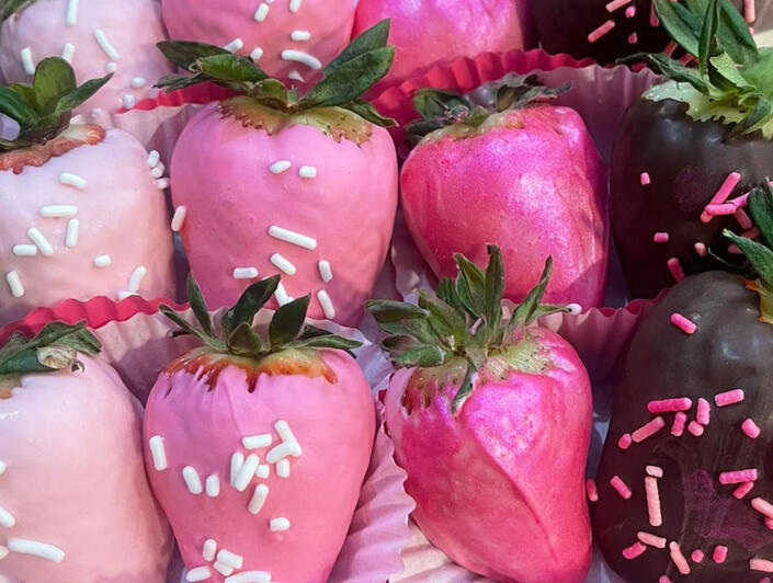 White chocolate dyed shades of pink and milk chocolate strawberries lightly dusted with sprinkles.